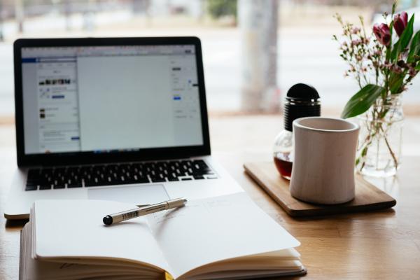 Open laptop and notebook with pen laying across it