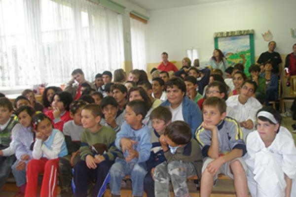 A large group of younger children sitting in rows inside a room