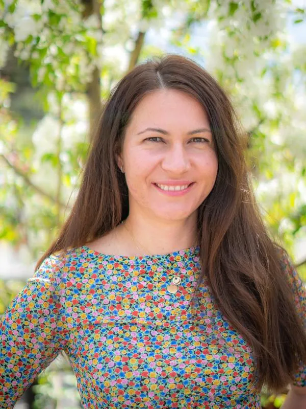 White women with long brown hair standing in front of tree background