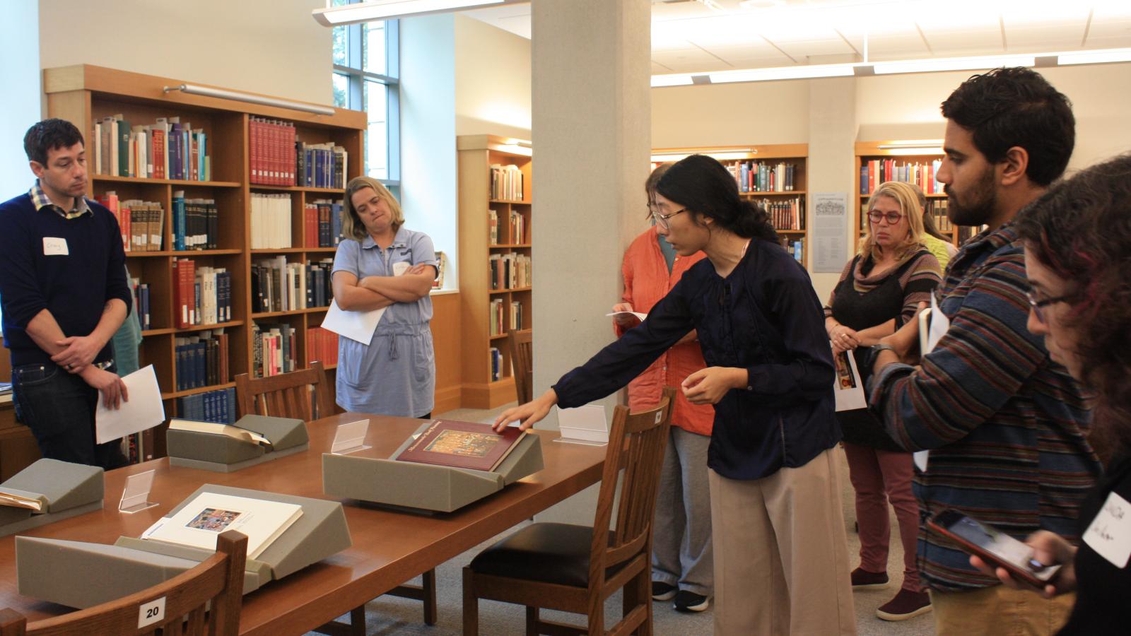 Graduate student Di Wang showing visiting teachers items from Thompson Library's the Special Collections.