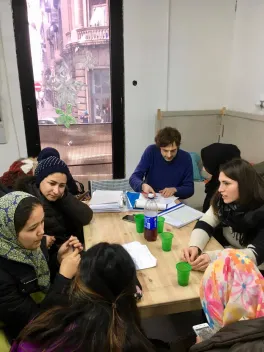Group of women sitting around a table, talking to one another